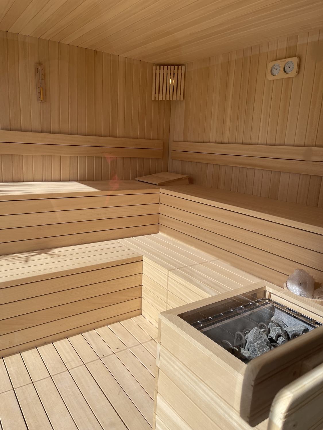 Sauna me sobë guri në qoshe dhe stola të gjerë
